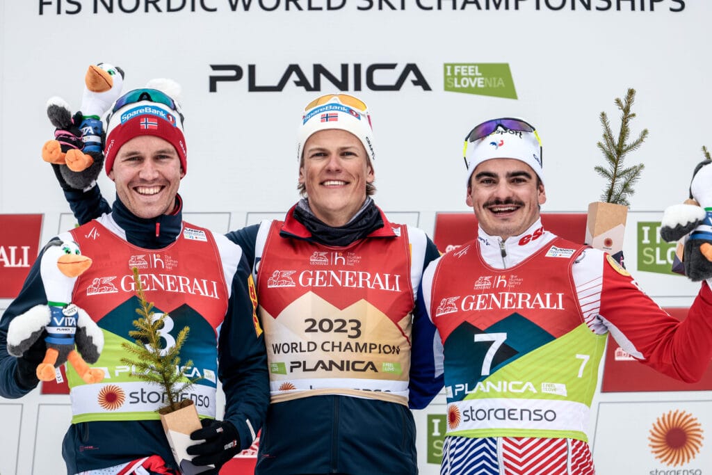 Pål Golberg (til venstre)), Johannes Høsflot Klæbo og Jules Chappaz på pallen etter VM-sprinten i Planica 2023. Løpet ble franskmannens store internasjonale gjennombrudd. Foto:Modica/NordicFocus