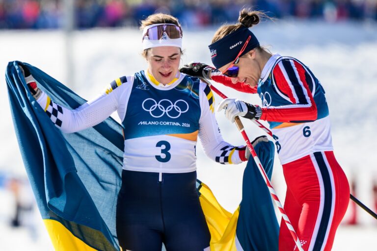 Ebba Andersson of Sweden and Heidi Weng of Norway celebrate after competing in the women's 50km classic technique cross-country skiing race during day 16 of the 2026 Winter Olympics on February 22, 2026 in Val di Fiemme. Photo: Maxim Thore / BILDBYRÅN